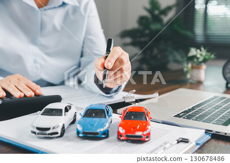 Businesswoman signing car insurance document or lease paper. Writing signature on contract or agreement. Buying or selling new or used vehicle. Car keys on table. Warranty or guarantee. Businesswoman signing car insurance document or lease paper. Writing signature on contract or agreement. Buying or selling new or used vehicle. Car keys on table. Warranty or guarantee. 130678486