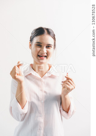 Asian woman rejoicing, looking happy, champion, fist pump gesture, standing over white background. young woman had happy, positive expression on her face, highlighted by bright smile. 130678528