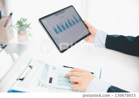 Accountant working on desk using calculator for calculate finance report in office. business finance, calculate tax by organizing financial documents, tracking income investment, accounting by hand. Accountant working on desk using calculator for calculate finance report in office. business finance, calculate tax by organizing financial documents, tracking income investment, accounting by hand. 130678653