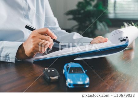 Customer signing insurance document lease agreement table, writing signature contract buying selling new or used vehicle, with car keys, warranty papers, guarantee included in transaction. 130679028