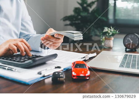 Businesswoman signing car insurance document or lease paper. Writing signature on contract or agreement. Buying or selling new or used vehicle. Car keys on table. Warranty or guarantee. 130679029