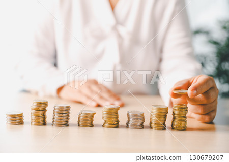 Hand places coin into saving jar, representing how smart finance, investment, banking practices turn money, cash, currency into financial wealth drives business growth and strengthens the economy. 130679207