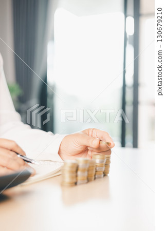 Hand places coin into saving jar, representing how smart finance, investment, banking practices turn money, cash, currency into financial wealth drives business growth and strengthens the economy. Hand places coin into saving jar, representing how smart finance, investment, banking practices turn money, cash, currency into financial wealth drives business growth and strengthens the economy. 130679210