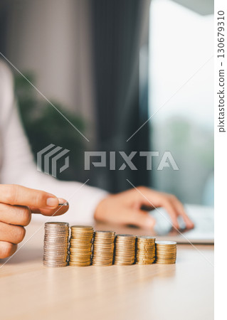 Hand places coin into saving jar, representing how smart finance, investment, banking practices turn money, cash, currency into financial wealth drives business growth and strengthens the economy. 130679310