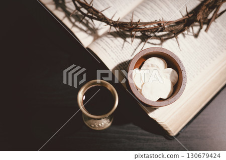 Communion bread and wine with the Holy Bible and crown of thorns, symbolizing the sacrifice of Jesus Christ, the passion, salvation and Christian faith in the Eucharist and Lord Supper. 130679424