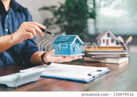 Female hand holds small miniature toy house, symbolizing woman dream of moving into her own home-real estate concept represents property investment, mortgage planning, insurance for secure future. 130679516