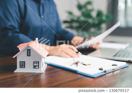 Female hand holds small miniature toy house, symbolizing woman dream of moving into her own home-real estate concept represents property investment, mortgage planning, insurance for secure future. 130679517
