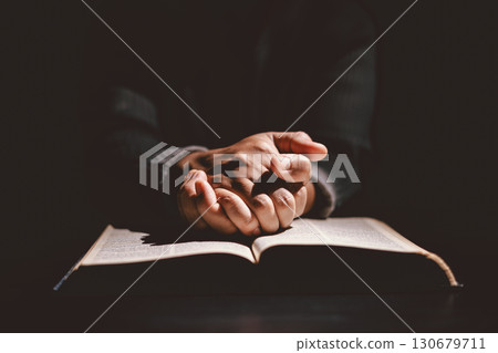 Hands folded in prayer on the Holy Bible, symbolizing faith, devotion, Christianity, hope, and spiritual strength. Concept of worship, meditation and trusting God Word. Hands folded in prayer on the Holy Bible, symbolizing faith, devotion, Christianity, hope, and spiritual strength. Concept of worship, meditation and trusting God Word. 130679711