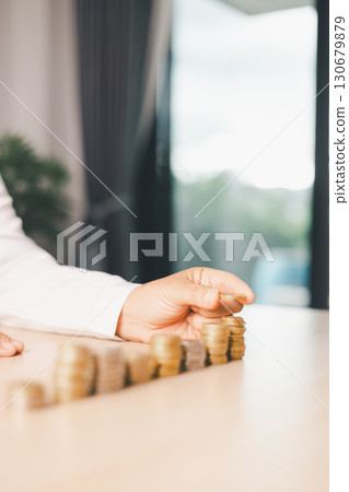 Hand places coin into saving jar, representing how smart finance, investment, banking practices turn money, cash, currency into financial wealth drives business growth and strengthens the economy. 130679879