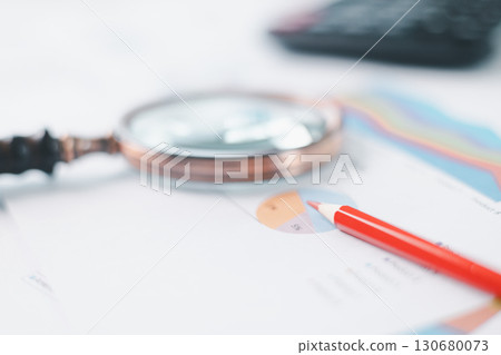 Magnifying glass with calculator and pen on financial reports with charts, graphs at office desk. Concept of business analysis, accounting audit, financial accuracy, transparency, corporate strategy. Magnifying glass with calculator and pen on financial reports with charts, graphs at office desk. Concept of business analysis, accounting audit, financial accuracy, transparency, corporate strategy. 130680073
