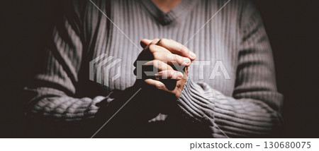 Person clasping hands in prayer, symbolizing faith, hope, spirituality, devotion, inner strength, meditation, belief, healing and the power of trust during difficult times in life. 130680075