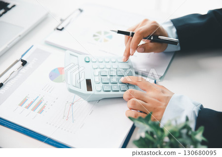 Accountant working on desk using calculator for calculate finance report in office. business finance, calculate tax by organizing financial documents, tracking income investment, accounting by hand. Accountant working on desk using calculator for calculate finance report in office. business finance, calculate tax by organizing financial documents, tracking income investment, accounting by hand. 130680095