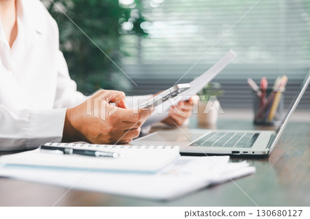 Businesswoman manages finances by using banking and accounting system to calculate costs, taxes, investments, illustrating a business, finance, and real estate concept focused on financial strategy. Businesswoman manages finances by using banking and accounting system to calculate costs, taxes, investments, illustrating a business, finance, and real estate concept focused on financial strategy. 130680127