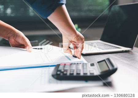 Office businesswoman hand to operate calculator analyzing financial data, counting costs on desk. accounting, financial analysis for business budget planning, calculation support, finance management. 130680128
