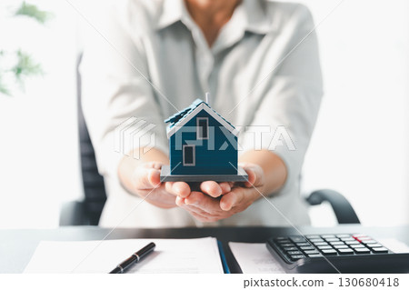Real estate agent agree to buy home to clients agency office. House model, real estate agent, customer discussing for contract to buy house, insurance, loan real estate background. Concept agreement. Real estate agent agree to buy home to clients agency office. House model, real estate agent, customer discussing for contract to buy house, insurance, loan real estate background. Concept agreement. 130680418