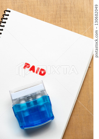 Red Paid Stamp on White Notebook Paper Close Up 130682049