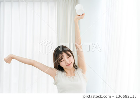 Smiling Asian woman drinking hot water, coffee, hot drink, cafe au lait, cafe latte at home in the morning Smiling Asian woman drinking hot water, coffee, hot drink, cafe au lait, cafe latte at home in the morning 130682115