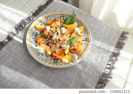 Fruit salad with cheese and honey on porcelain plate with blue pattern. Baked fruits. Food and vitamins, healthy eating. Seasonal products. 130682321