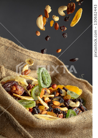 Dried tropical fruits and nuts in burlap bag. 130682443