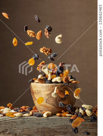 Dried nuts and raisins in a wooden bowl. 130682465