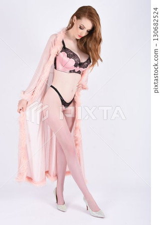 Tall, beautiful, shapely redheaded model in pink lingerie, isolated against a pink background Tall, beautiful, shapely redheaded model in pink lingerie, isolated against a pink background 130682524
