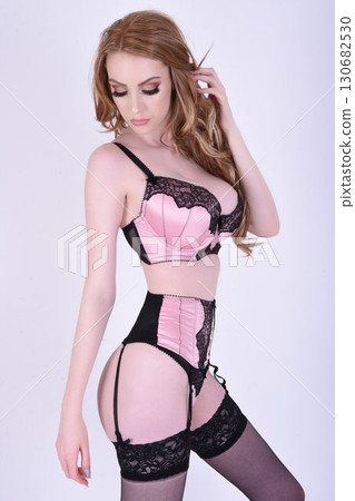 Tall, beautiful, shapely redheaded model in pink lingerie, isolated against a pink background Tall, beautiful, shapely redheaded model in pink lingerie, isolated against a pink background 130682530
