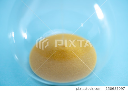 Telling time with an hourglass with sand flowing within a distance. Transparent hourglass. 130683097