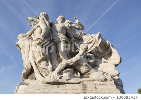 Rome, Italy - August 16, 2019: Marble composition on the bridge of Victor Emmanuel II over the Tiber River in Rome, symbolizing freedom and unity. Rome, Italy - August 16, 2019: Marble composition on the bridge of Victor Emmanuel II over the Tiber River in Rome, symbolizing freedom and unity. 130683417