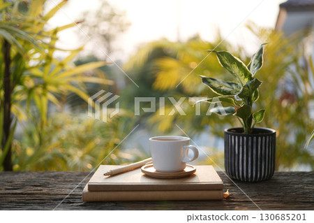 White coffee cup and notebook and potted plant outdoor cozy working space 130685201