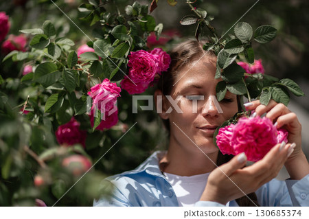Roses Woman Nature: Woman touches rose bush outside on sunny day, enjoying beauty. Roses Woman Nature: Woman touches rose bush outside on sunny day, enjoying beauty. 130685374
