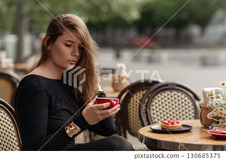 Cafe Coffee Woman: Afternoon break with coffee, cake, at outdoor cafe, enjoying moments. 130685375