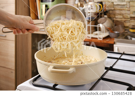 Cooking delicious noodles with mushrooms in a cozy kitchen during the evening 130685428
