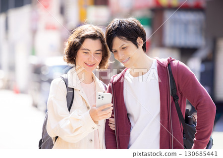 Inbound: Foreigners strolling around the streets of Tokyo while looking at their smartphones 130685441