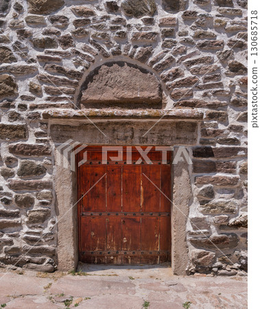 Historic Stone Wall with Arched Wooden Door 130685718