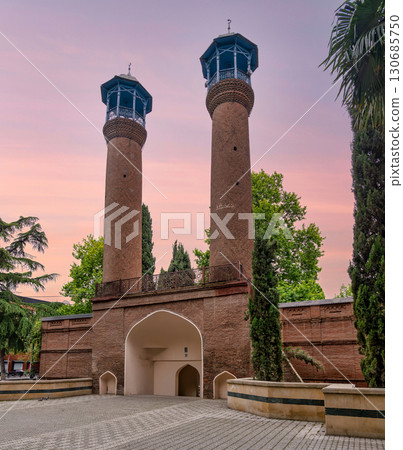 Juma Mosque Minarets, Ganja, Azerbaijan. Historic brick towers with blue balconies and archway under a pastel sky Juma Mosque Minarets, Ganja, Azerbaijan. Historic brick towers with blue balconies and archway under a pastel sky 130685750