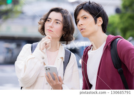 Inbound: Foreigners strolling around the streets of Tokyo while looking at their smartphones 130685791