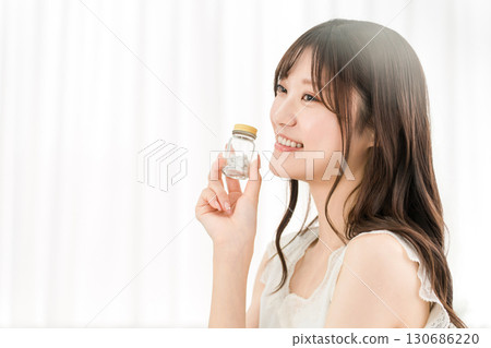 微笑的亞洲女人拿著一瓶藥/補品 130686220