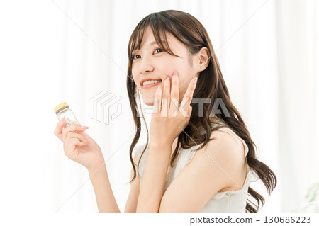 微笑的亞洲女人拿著一瓶藥/補品 130686223
