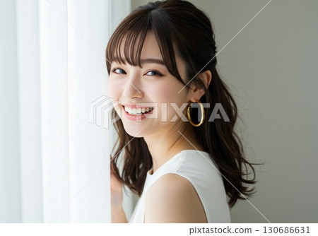 Portrait of a smiling young woman smiling by the window 130686631