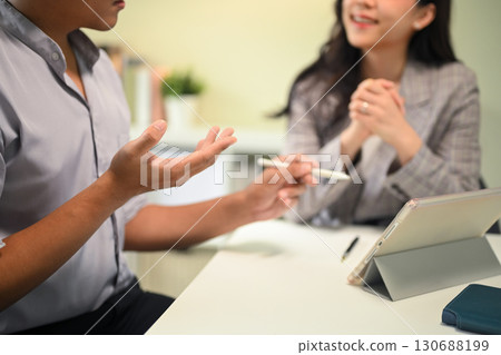 Business partners brainstorming ideas and reviewing data on a digital tablet during a meeting 130688199