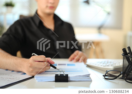 Close up of businessman reviewing documents and highlighting data in office 130688234