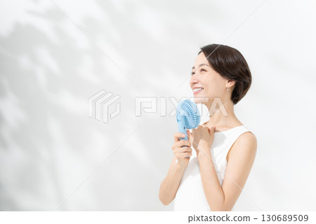 A woman who cools down with a handy fan 130689509