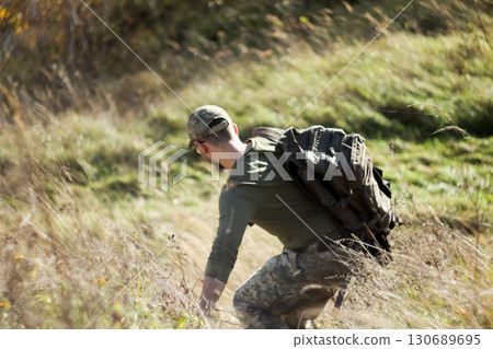 a NATO soldier from Ukraine or the USA from the back in the mountains grass. NATO soldier physical training mountain. military cooperation descending training. tactical training military exercise a NATO soldier from Ukraine or the USA from the back in the mountains grass. NATO soldier physical training mountain. military cooperation descending training. tactical training military exercise 130689695