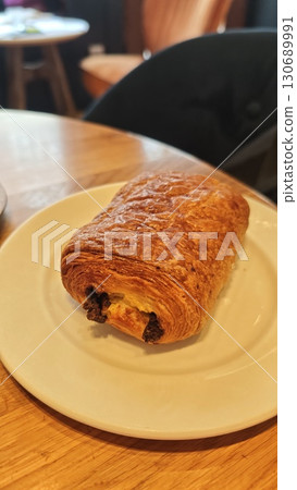 Freshly baked pain au chocolat served on a white plate in a cozy cafe setting Freshly baked pain au chocolat served on a white plate in a cozy cafe setting 130689991