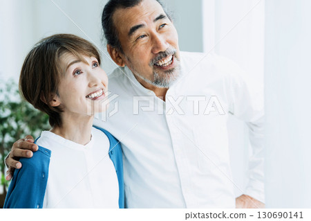 Senior couple looking outside by the window Senior couple looking outside by the window 130690141