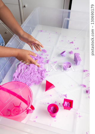 Child playing with purple kinetic sand and molds indoors Child playing with purple kinetic sand and molds indoors 130690179