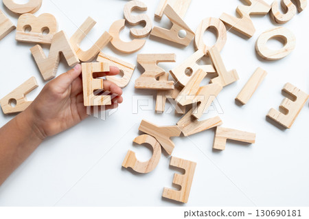 Child hand holding wooden alphabet letters on white background 130690181