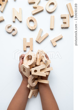 Child hands holding wooden alphabet letters on white background 130690189