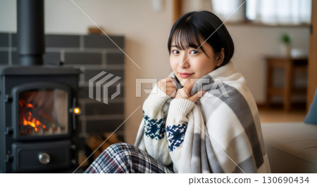 Portrait of a woman relaxing in front of a stove 130690434