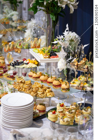 Delicate mini burgers, croissants, and canapes on a banquet table. Stylish appetizer display  130690584